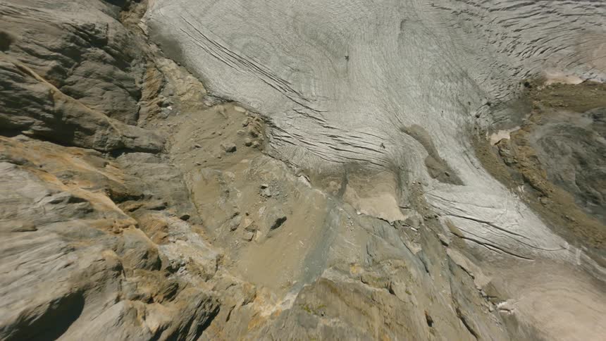 Adventurous aerial view of the ridges and slopes of a mountain peak under a bright blue sky