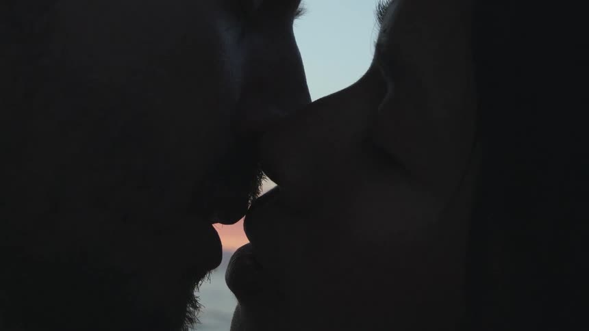 A couple make out while standing near the ocean