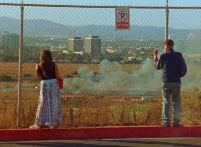Man and woman are standing by a fence outdoors