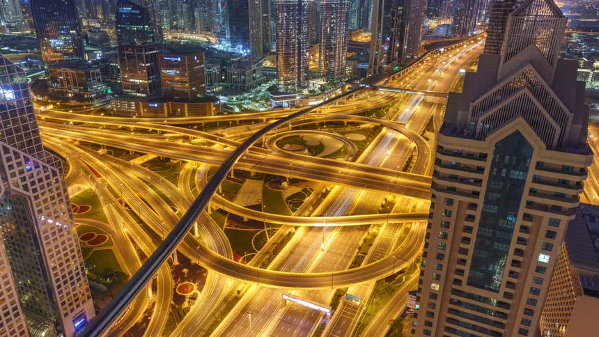 Traffic moves along a well lit roadway in a city