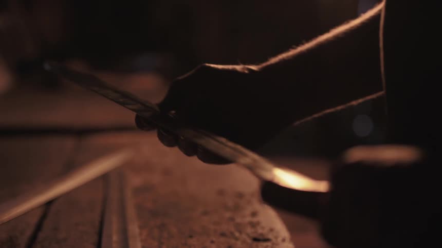 A man traces his hand across a long sword