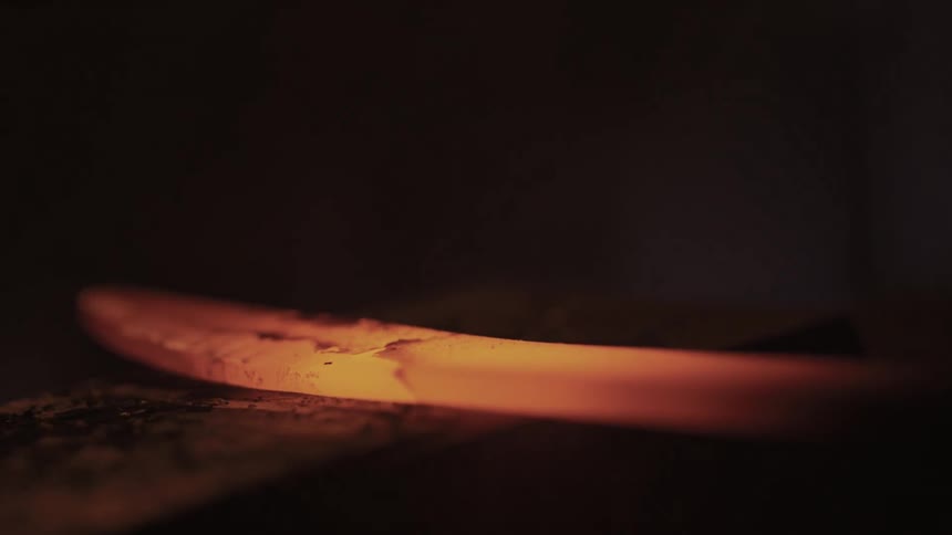 Mallet hitting the end of a red hot heated sword