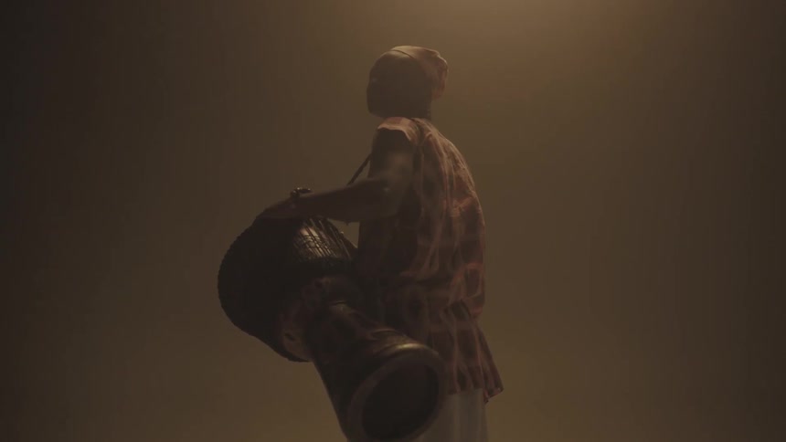 Man standing in dim room holding a bongo drum