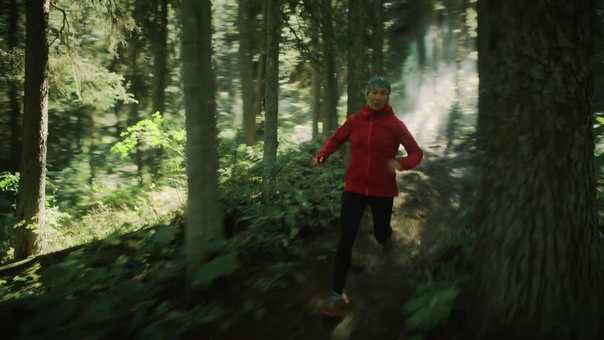 A woman runs through a hilly forest
