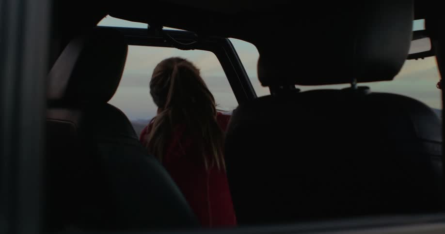 A woman gets out of her parked car in the woods