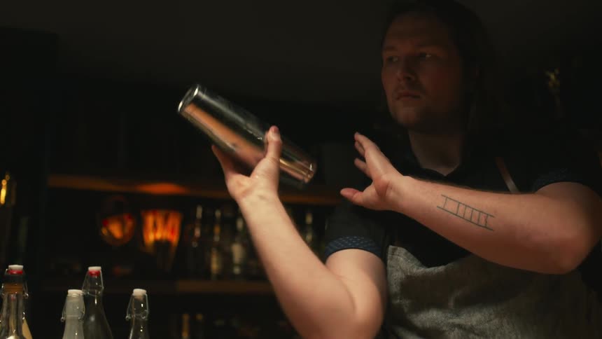 A white man is bar tendering and making drinks at the bar