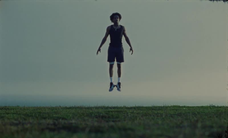 Man floats into the air in a field under an overcast sky