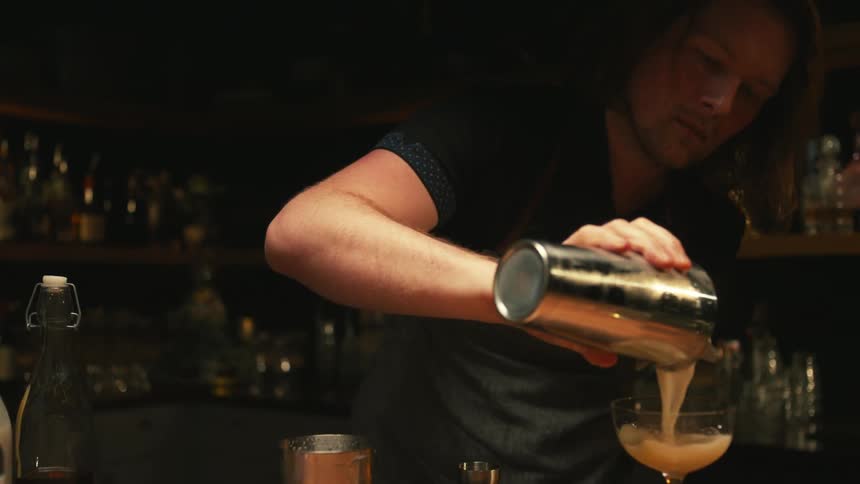 A male bartender preparing a drink in a bar