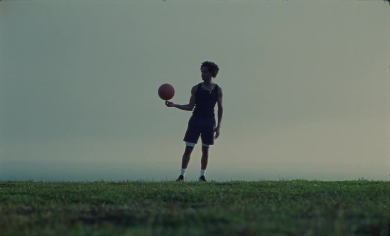 Youngblack man is playing with a basketball outside in the nature area