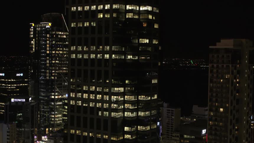 Light shines from lit rooms in downtown skyscrapers at night