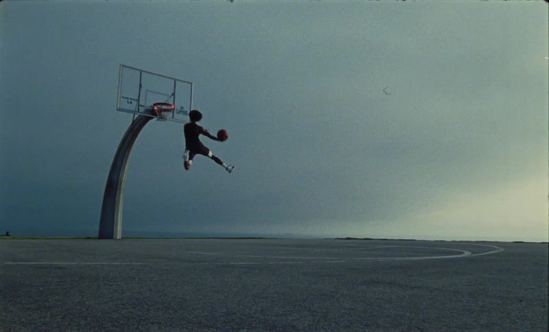 A man is playing basketball by himself outdoors