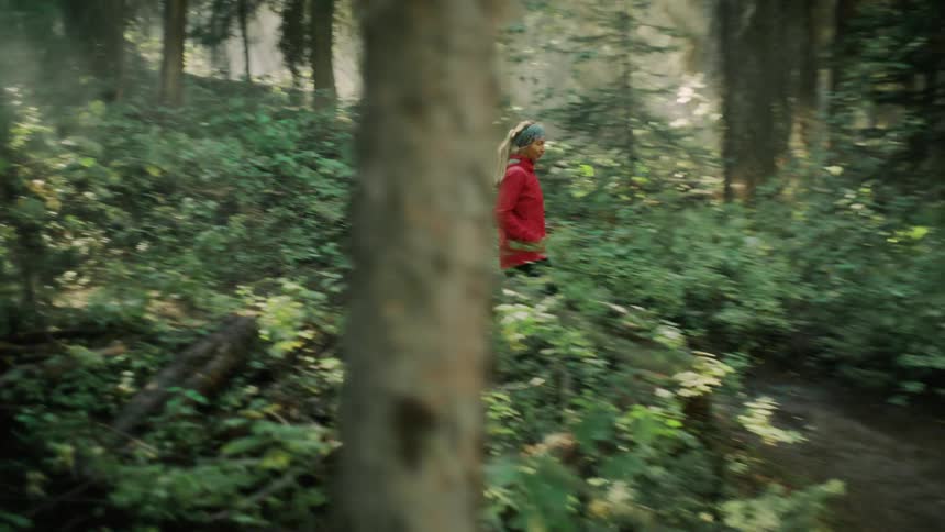 A woman jogs through a verdant woodland during the day