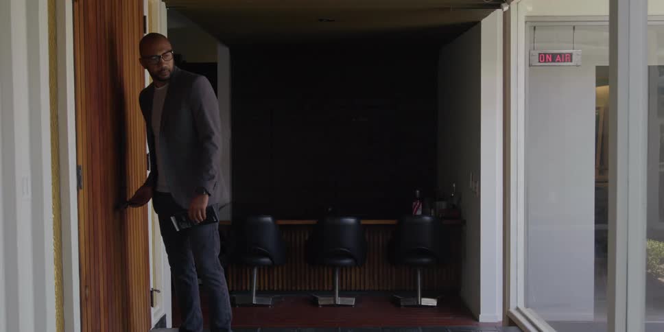 A young black man is walking into his work office in the day time