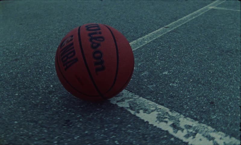 Basketball rolls over flaking paint designating corner of the basketball court