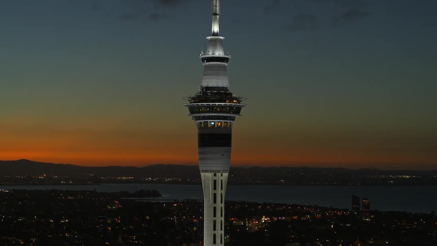 Space needle towers over city hugging shore contrasting with red afterglow on the horizon