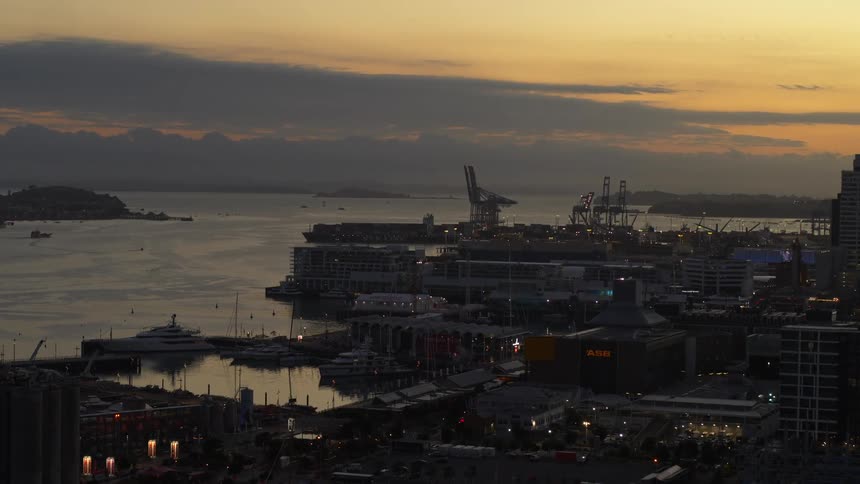 Aerial view of the port and harbor on the docks of a waterfront city next to the ocean at evening