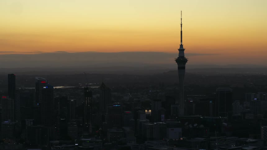 The silhouette of the sky tower in skycity auckland against a golden sky at sunset