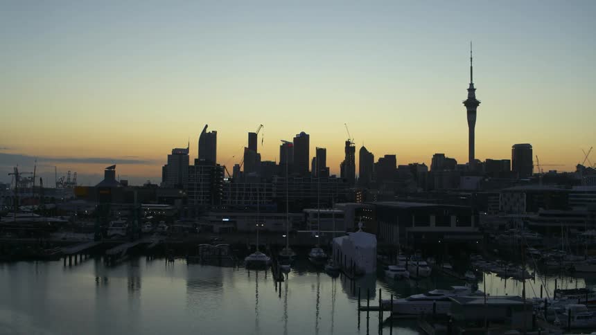 Aerial view of a television transmission tower on the city skyline of a waterfront city at evening
