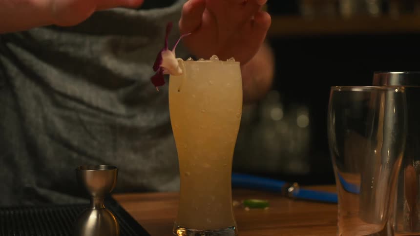 A bartender garnishes a cocktail with a flower