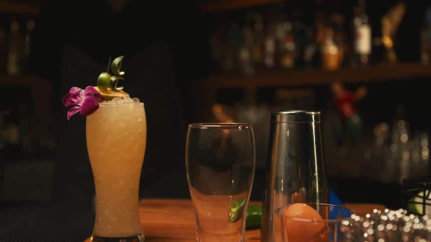 A cocktail served on a tall grass resting on the counter at a bar