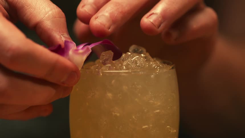 A person is garnishing a drink with a flower