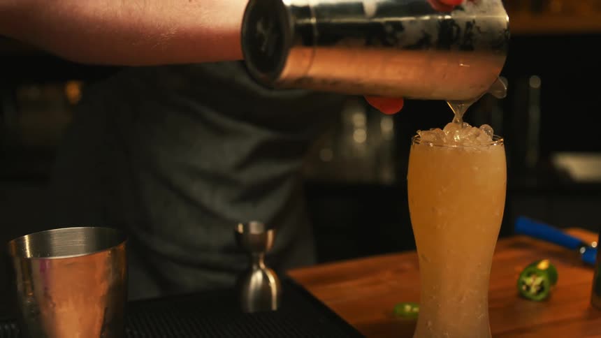 A man is making alcoholic drinks at a bar