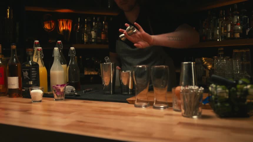 Bartender mixes drinks and cocktails on the counter of a dimly lit bar