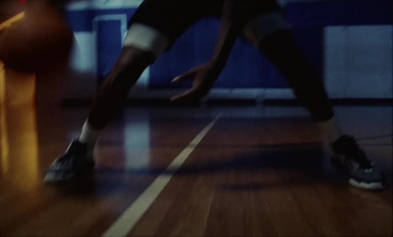 A man dribbles a basketball on a court