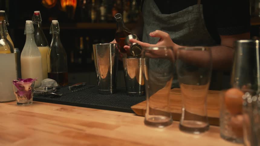 A bartender pours alcohol into a shaker as he makes a drink