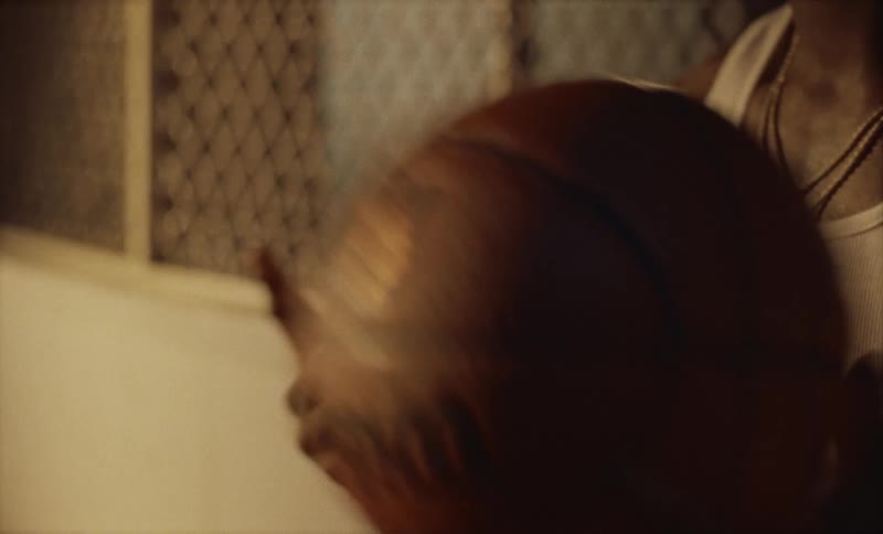 Man sitting on bench near window spins basketball on the end of his finger
