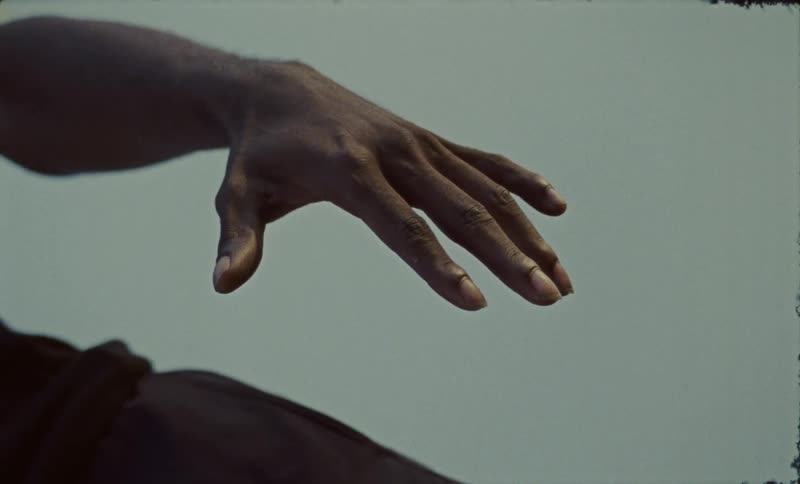 Mans hand floats above his thigh under an overcast sky