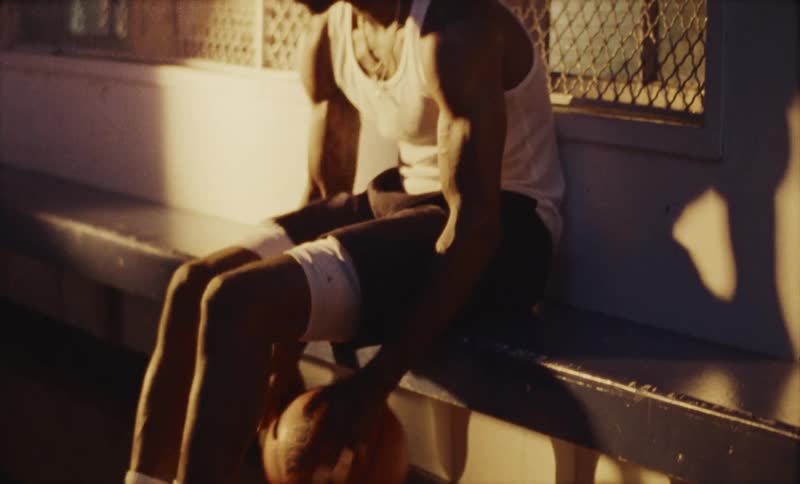 A man is dribbling a basketball while sitting