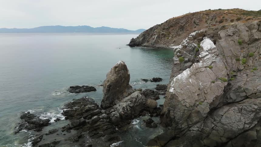 A rock formation along a rocky coastline during the day