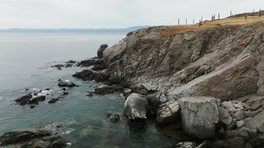 Brown grasses cover top of promontory as mist obscures distant shore