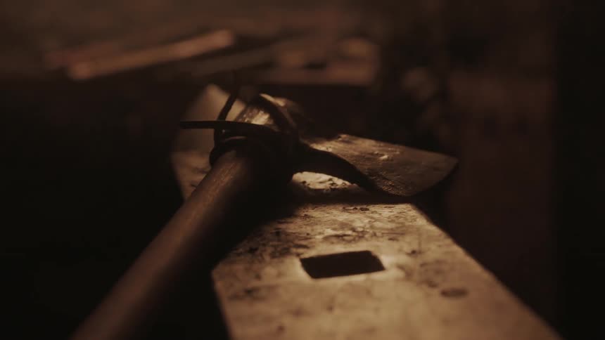 Firelight flickering across an anvil and axe