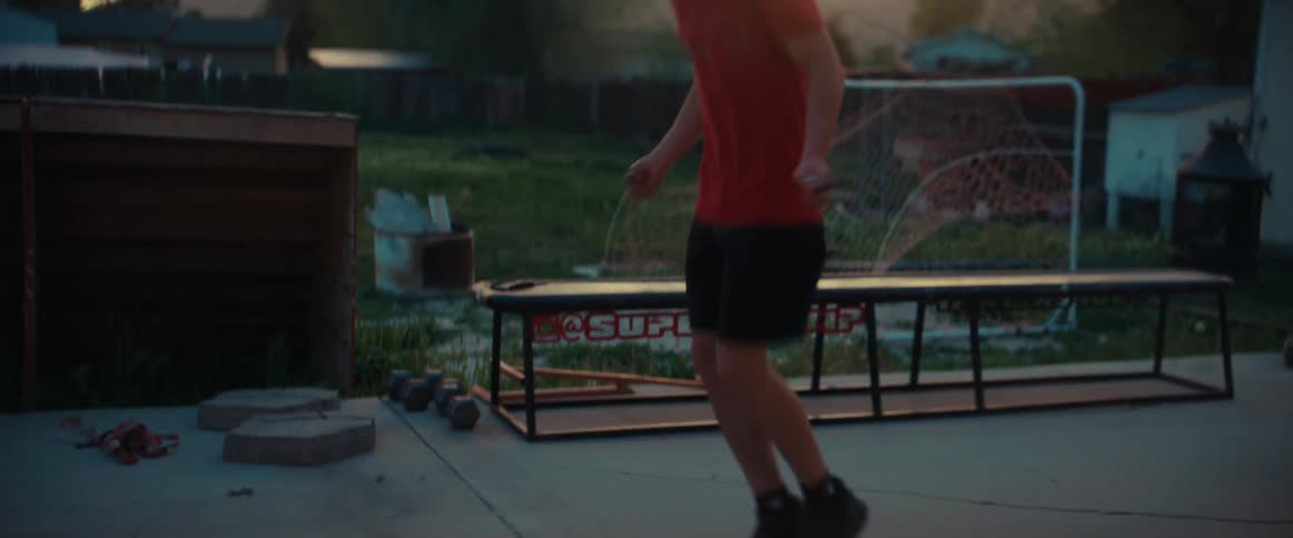 A young man jumps rope on his back patio at sunset
