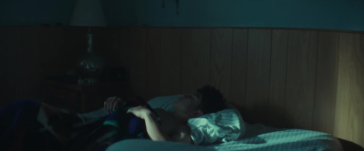 A teenage boy turning and trying to get comfortable while sleeping in a bed