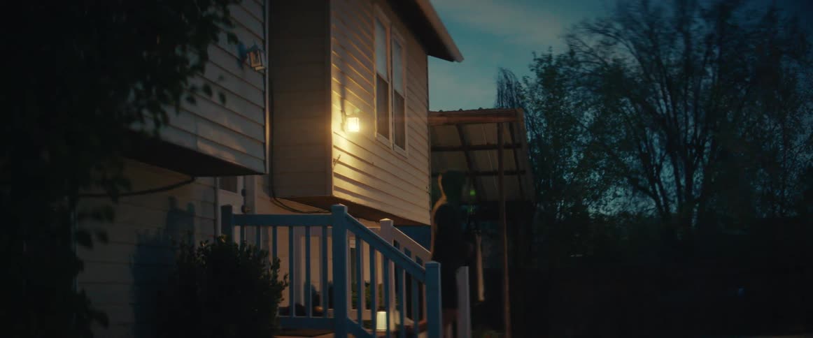 A young man leaves his house at dawn puts up his hood and jogs off