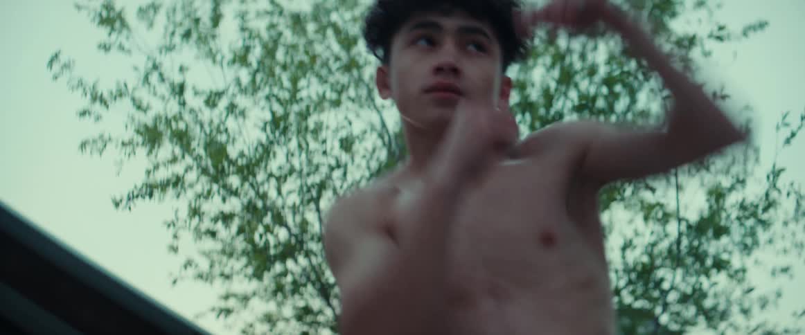 Young shirtless teenager shadow boxing on the backyard at evening