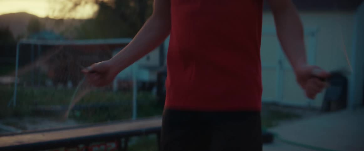 Young teenager rope jumping on the backyard of a house at evening