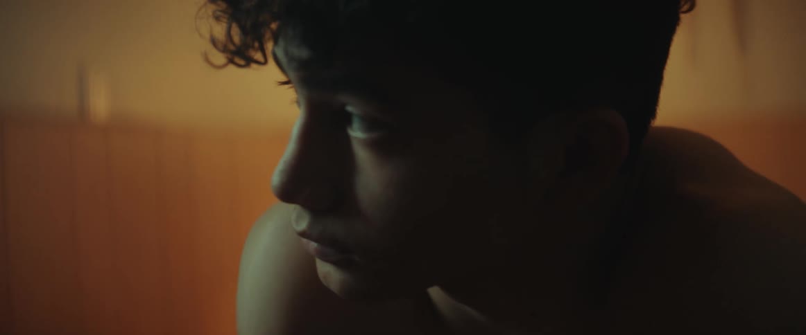A sleepy teen boy rubbing his face while waking up