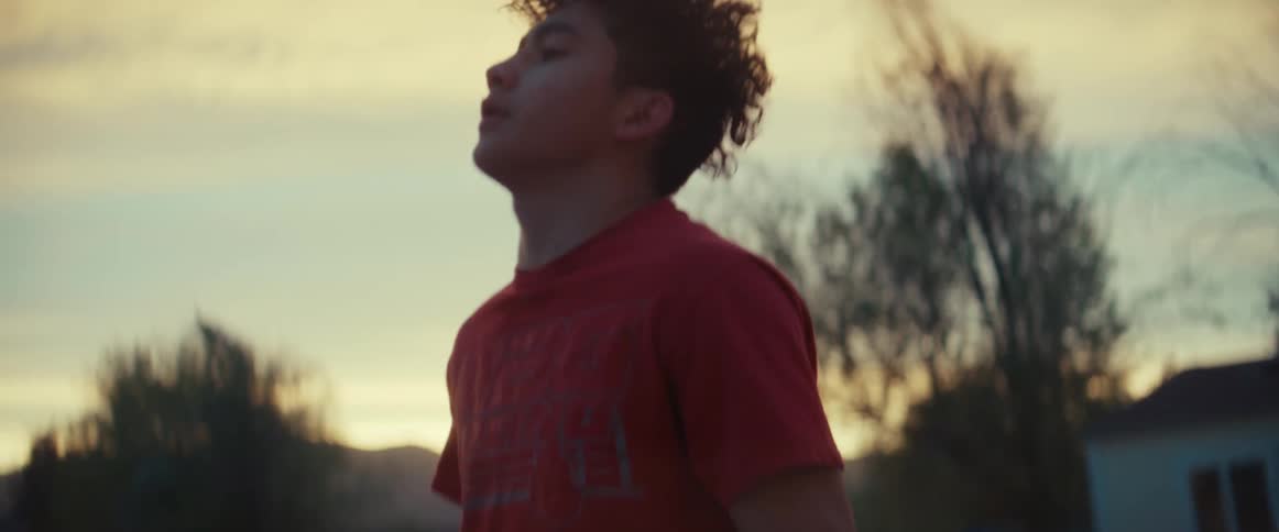 A teenage boy jumps rope outside his house as the sun sets