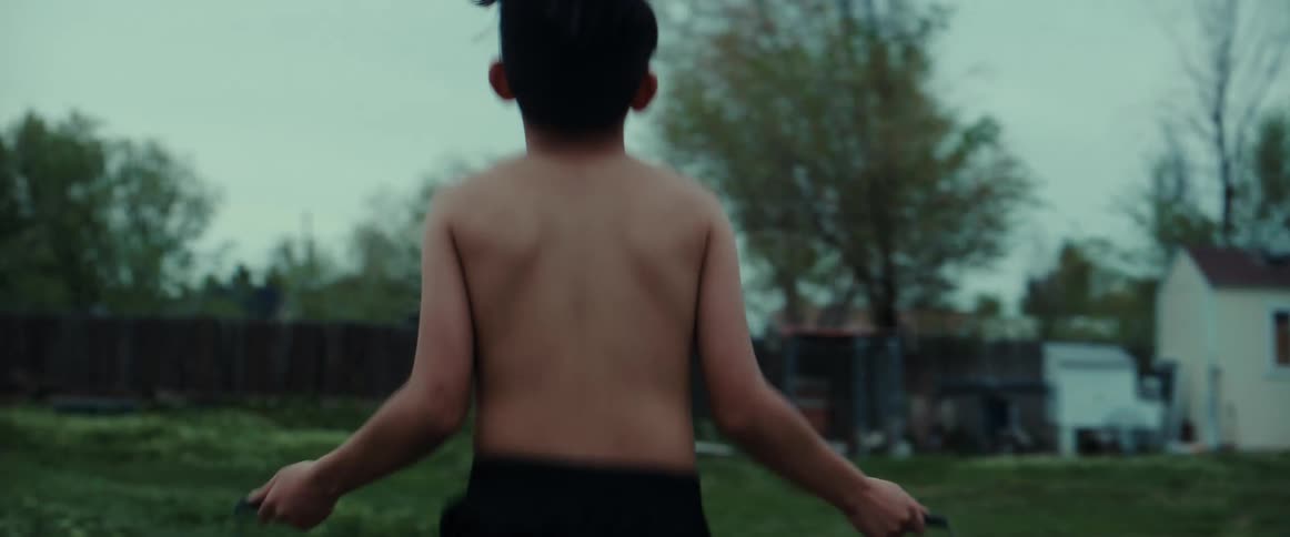 Shirtless boy jumps rope in the garden