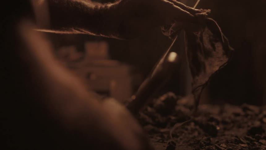 A man polishes a sword near a fire