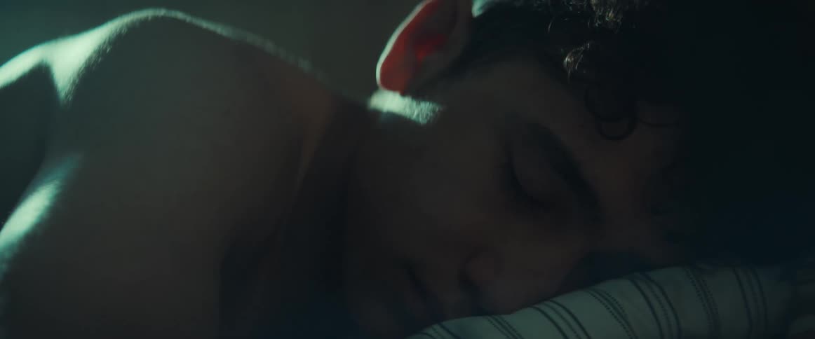 A teen boy turning over while sleeping in a bed
