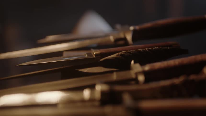 A row of knives sit on an anvil