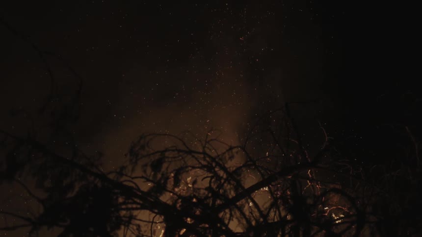 Flames, smoke and embers rise from a large bonfire