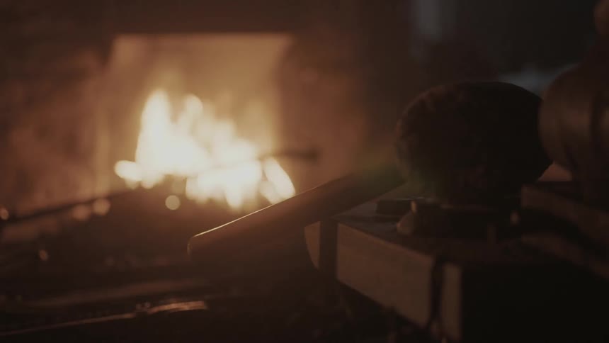 A man removes a rod and stirs a fire