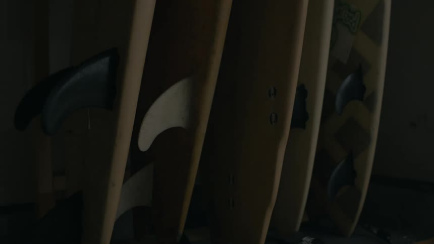 Surfboards with fins leaning against a wall