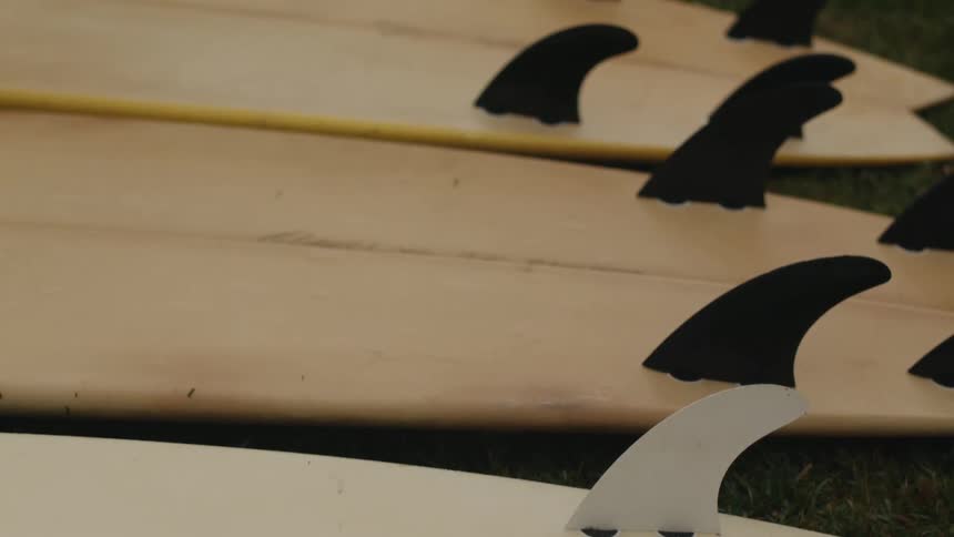 Surfboards with fins attached laying on the grass